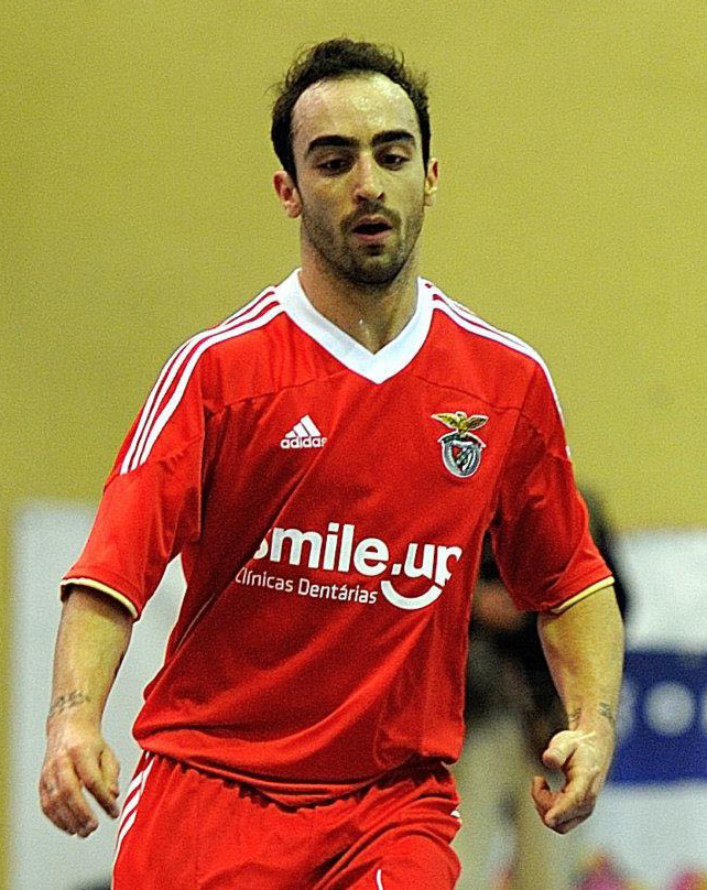 Ricardinho in a red Benfica kit during a match, focused expression against a blurred indoor-court background
