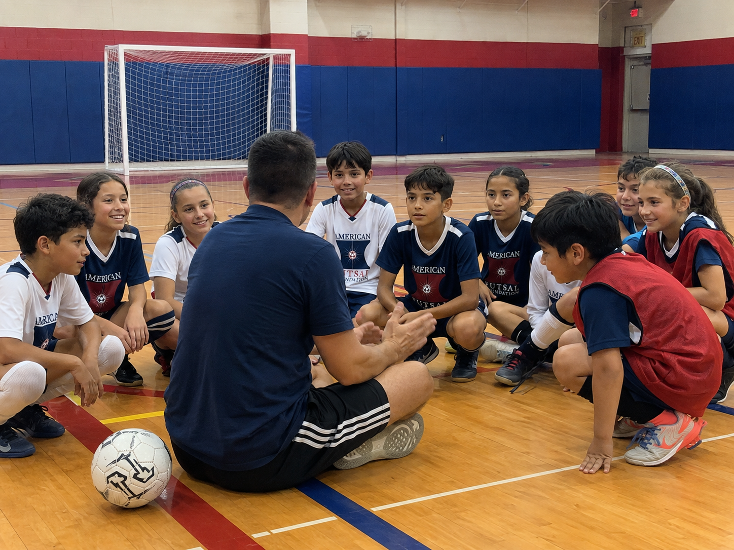 Youth futsal players gathered with a coach in a school gym